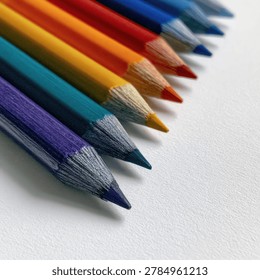A vibrant array of colored pencils, showcasing a spectrum of colors from purple to blue, arranged in a diagonal line on a textured white background.