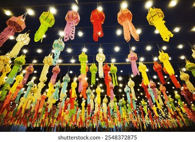 a vibrant array of colorful paper lanterns hanging from above, illuminated against a night sky. The lanterns are in various shapes and colors, creating a festive and lively atmosphere.  - Powered by Shutterstock