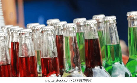 A vibrant array of glass bottles filled with colorful liquids arranged in a row at a market or store setting.
