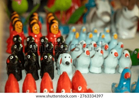 A vibrant array of hand painted animal miniatures including dogs, birds, and penguins crafted from traditional terracotta. Folk art sculptures playful, rustic charm