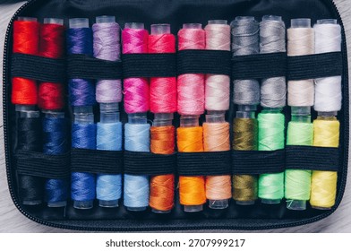 A Vibrant Array of Thread Spools Organized Neatly in a Compact Storage Case for Easy Access and Creative Sewing Projects