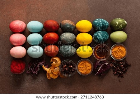 A vibrant assortment of Easter eggs rests on a surface, beautifully dyed in various colors. Natural dye ingredients, such as beets, turmeric and hibiscus, red cabbage and onion peel, vinegar
