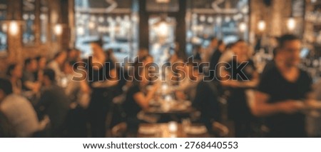 A vibrant, blurred background image capturing the energetic atmosphere of people socializing and dining in a busy restaurant or bar during the evening.