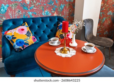 Vibrant Cafe Corner with Blue Velvet Sofa and Orange Table.Cozy Coffee Setting with Floral Wallpaper and Navy Tufted Loveseat. High quality photo - Powered by Shutterstock - Get 15% off with code: PIKWIZARD15