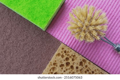 Vibrant cleaning tools on a textured pink backdrop, featuring a green sponge, yellow brush with metal handle, and brown porous sponge. Ideal for hygiene and cleanliness themes. - Powered by Shutterstock