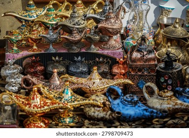 A vibrant close-up captures an array of intricately designed genie lamps, ceramic teapots, and metal souvenir boxes. These traditional items are displayed for sale in a bustling market stall in Baku, Azerbaijan.