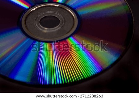 Vibrant closeup of a CD surface displaying colorful rainbow light reflections and diffraction patterns, abstract technology background with vivid spectrum lines on a dark backdrop.
