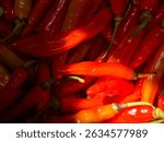 Vibrant close-up of fresh red and orange chili peppers with natural shine and texture. Perfect for culinary themes, spicy food concepts, agricultural produce, or as a colorful organic background 
