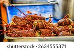 Vibrant close-up of freshly prepared European Lobsters (Homarus gammarus) piled in a metal tray, showcasing their rich red and brown shells. Ideal for culinary, seafood, and gourmet themes.