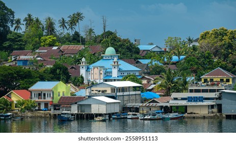 vibrant coastal village with colorful houses, a mosque, boats, and lush greenery. - Powered by Shutterstock