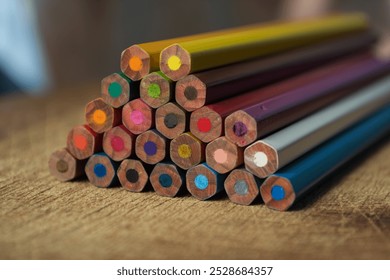 A vibrant collection of colored pencils, meticulously arranged in a triangular pattern, resting on a wooden tabletop - Powered by Shutterstock