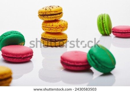 Vibrant and colorful assortment of macarons stacked and artfully arranged on a pristine white surface, creating an enticing display with reflections.