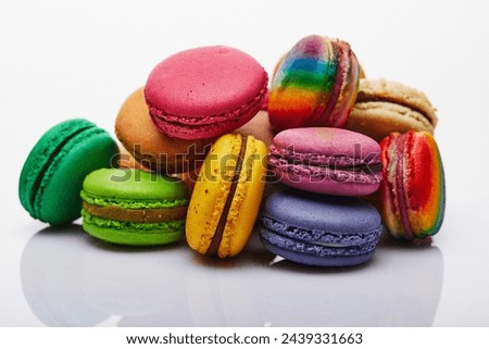 Vibrant and colorful assortment of macarons stacked and artfully arranged on a pristine white surface, creating an enticing display with reflections.