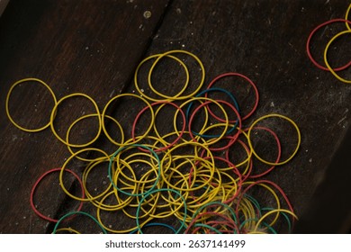 A vibrant and colorful collection of yellow, red, and blue rubber bands are beautifully scattered across a wooden surface, creating an intriguing, striking, and visually captivating display