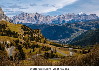 The vibrant colors of autumn adorn the rolling hills of the Dolomites as winding roads weave through the landscape. Majestic peaks rise in the background, Passo Rolle, Trento - Powered by Shutterstock