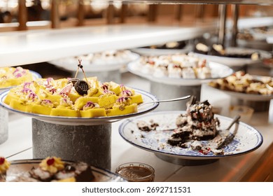 A vibrant dessert buffet features assorted sweets, including cakes and pastries, beautifully arranged on silver platters ready for guests to enjoy at a lively celebration