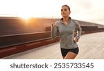 A vibrant and determined young woman joyfully sprints along a scenic track at sunset, perfectly showcasing her unwavering commitment to fitness and overall wellbeing, embodying the essence of health