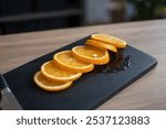 A vibrant display of freshly sliced orange segments is arranged on a sleek black cutting board, reflecting a modern kitchen atmosphere filled with natural light.