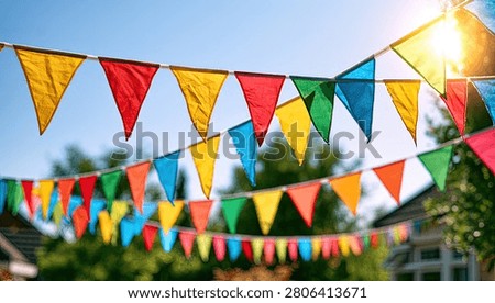 A vibrant display of triangular bunting flags in various colors strung across a clear blue sky, with sunlight glinting.