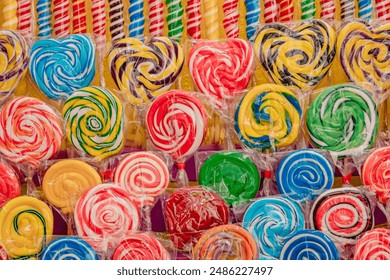 A vibrant display of various brightly colored swirled lollipops and wrapped candies, creating a cheerful scene. - Powered by Shutterstock