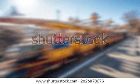 A vibrant and dynamic image capturing the blurred motion of a thrilling amusement park ride under a clear blue sky.