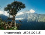 A vibrant and dynamic photograph capturing a person enjoying the famous “Swing at the End of the World” at La Casa del Árbol in Baños, Ecuador. The swing, attached to a treehouse perched high.