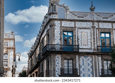 A vibrant exterior shot captures a corner of the iconic Casa de los Azulejos in Mexico City. The building's intricate tilework contrasts beautifully with the clear blue sky overhead
