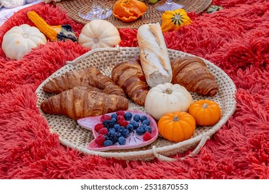 A vibrant fall picnic spread features colorful seasonal foods—bright pumpkins, apples, charcuterie, fresh bread, cheese, and warm drinks. Surrounded by golden leaves and cozy blankets. - Powered by Shutterstock