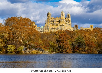 Vibrant fall trees frame a quiet Central Park lake with the San Remo towers on Central Park West, NYC; ideal for travel, luxury real estate, autumn lifestyle, editorial use
