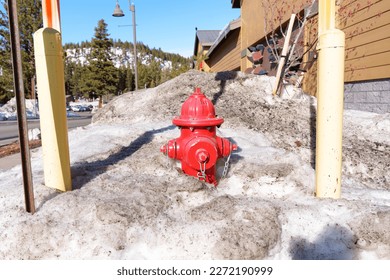 Vibrant fire hydrant in a layer of dirty snow. Reminder of the importance of maintaining clear access to fire hydrants during the winter months.
