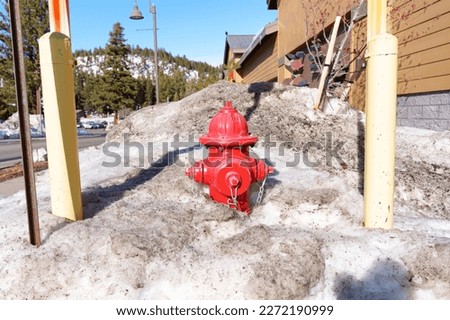 Vibrant fire hydrant in a layer of dirty snow. Reminder of the importance of maintaining clear access to fire hydrants during the winter months.