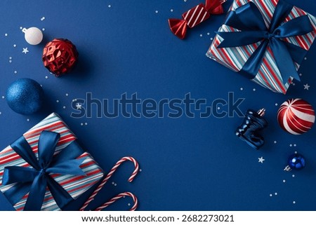Vibrant flat lay featuring wrapped gifts with ribbons, blue and red ornaments, candy canes, and festive decor on a dark blue background to evoke Christmas and New Year cheer
