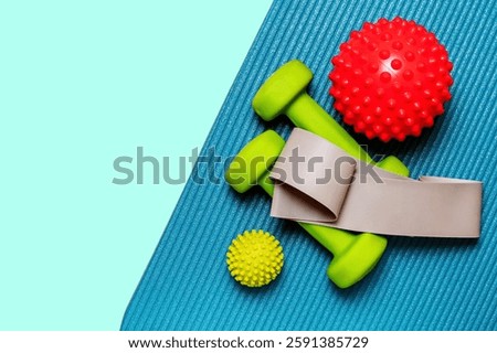 Vibrant flat lay showcasing a pair of lime green dumbbells, resistance band, and two spiky massage balls arranged on a teal yoga mat