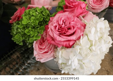 A vibrant floral arrangement showcasing pink roses, green hydrangeas, and white hydrangeas in a compact design, perfect for an elegant table centerpiece or wedding bouquet inspiration. - Powered by Shutterstock