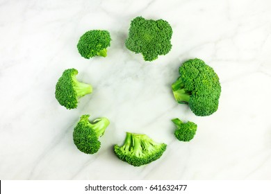 Vibrant green broccoli sprouts, shot from above on a white marble texture, forming a frame with a place for text