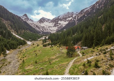 Vibrant green hills and towering snow-capped peaks create a breathtaking panorama in Piatra Craiului - Powered by Shutterstock