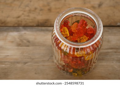 Vibrant gummy candies, gummy bears in transparent jar, offering burst of color and sweetness against rustic wooden background - Powered by Shutterstock