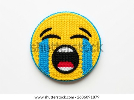 A vibrant, handmade patch featuring a crying emoji face, crafted with colorful yarn.