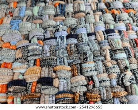 A vibrant handwoven textile featuring an array of colorful yarns intricately interlaced. The diverse textures and patterns highlight the beauty of craftsmanship and creativity in textile art.