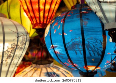 Vibrant, intricately patterned lanterns in assorted shapes and colors hang gracefully along a timeworn Vietnam market, showcasing exquisite traditional artistry.