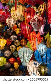 Vibrant, intricately patterned lanterns in assorted shapes and colors hang gracefully along a timeworn Vietnam market, showcasing exquisite traditional artistry.