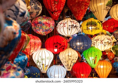 Vibrant, intricately patterned lanterns in assorted shapes and colors hang gracefully along a timeworn Vietnam market, showcasing exquisite traditional artistry.