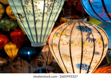 Vibrant, intricately patterned lanterns in assorted shapes and colors hang gracefully along a timeworn Vietnam market, showcasing exquisite traditional artistry.