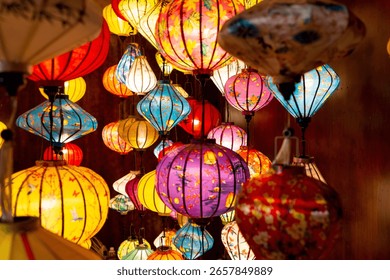 Vibrant, intricately patterned lanterns in assorted shapes and colors hang gracefully along a timeworn Vietnam market, showcasing exquisite traditional artistry.