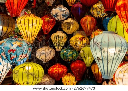 Vibrant, intricately patterned lanterns in assorted shapes and colors hang gracefully along a timeworn Vietnam market, showcasing exquisite traditional artistry.
