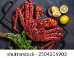 Vibrant king crab and assorted lemon slices arranged on a dark, rustic slate surface, cilantro, dark textured background, copy space, top view