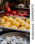 Vibrant lemons and tomatoes in trays, showcasing fresh produce ready for cooking and garnishing