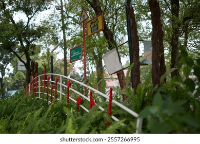 A vibrant musical-themed installation with red notes on a metal fence surrounded by lush green ferns and trees, capturing creativity and urban art in a serene park setting - Powered by Shutterstock