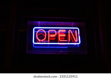 A vibrant neon sign with the word 'OPEN' shines brightly, illuminating the night - Powered by Shutterstock
