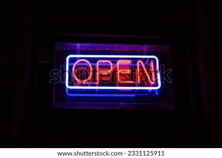 A vibrant neon sign with the word 'OPEN' shines brightly, illuminating the night